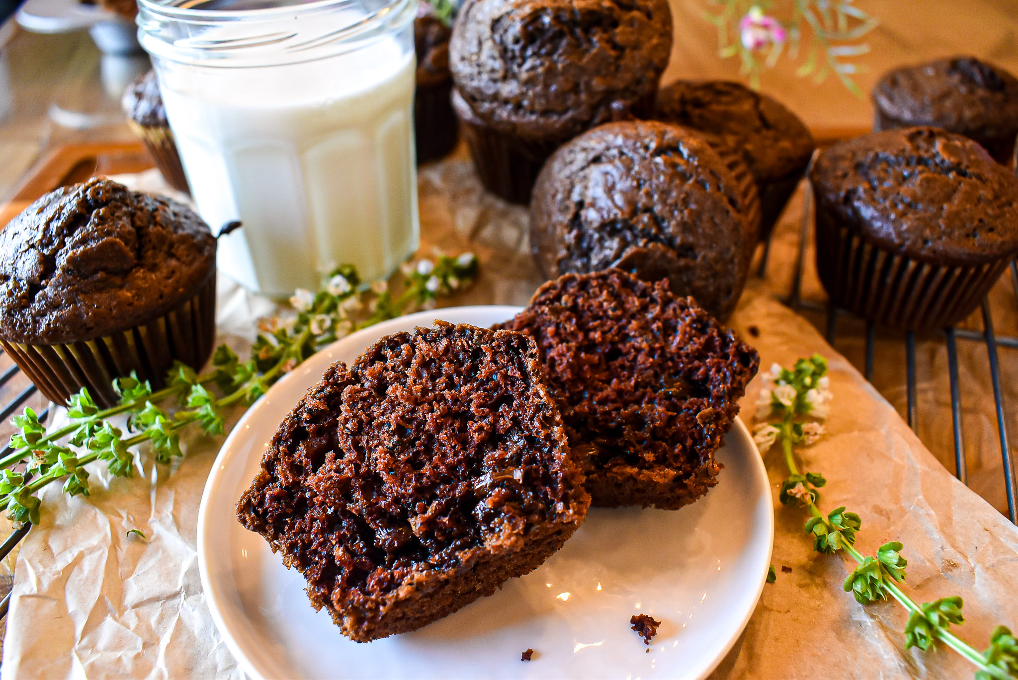 Chocolate muffins with one split open on a small plate next to a glass of milk