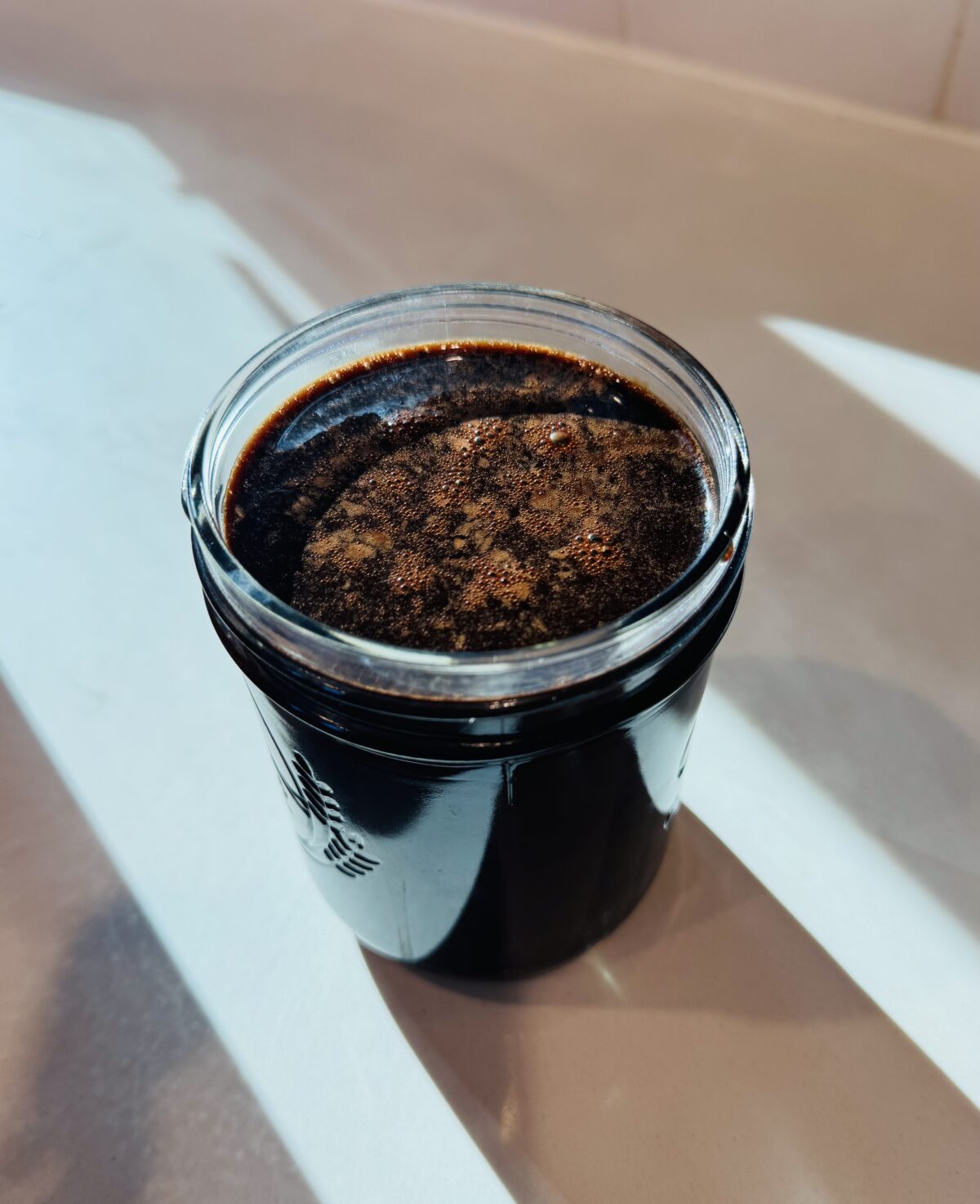 Glass mason jar filled with Chocolate Milk Concentrate topped with fine foam, set in bright sunlight