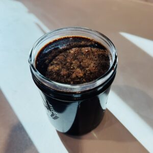 Glass mason jar filled with Chocolate Milk Concentrate topped with fine foam, set in bright sunlight
